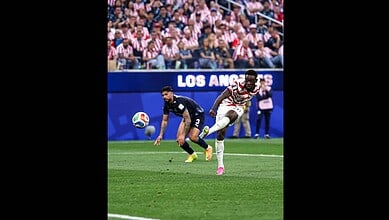 Striker in white and red jersey chasing the ball during a football match at the Los Angeles stadium.