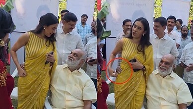 Women in yellow sarees engaging with elderly men at a public event in India.