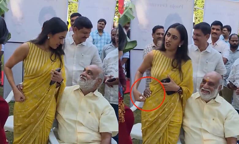 Women in yellow sarees engaging with elderly men at a public event in India.