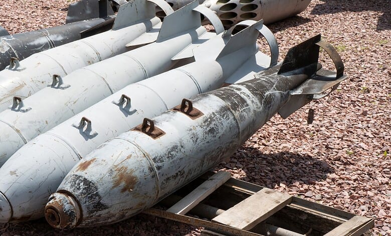 Explosive devices or missiles laid on the ground with rusted surfaces and metal fins.