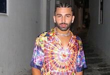 Man with styled hair and beard wearing a vibrant, patterned shirt in a narrow alleyway.