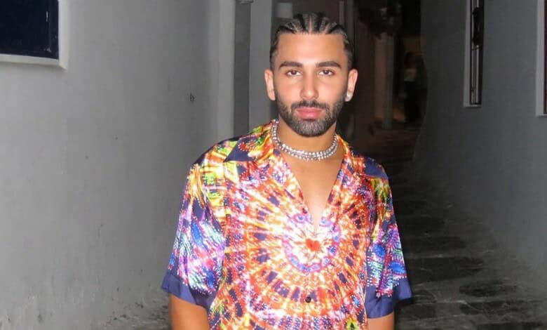 Man with styled hair and beard wearing a vibrant, patterned shirt in a narrow alleyway.