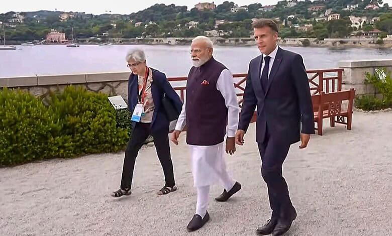 Indian Prime Minister Narendra Modi walking along a riverside with two officials, scenic background with.