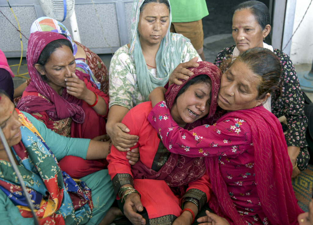 Women mourning and comforting each other during a communal gathering in Dehradun.