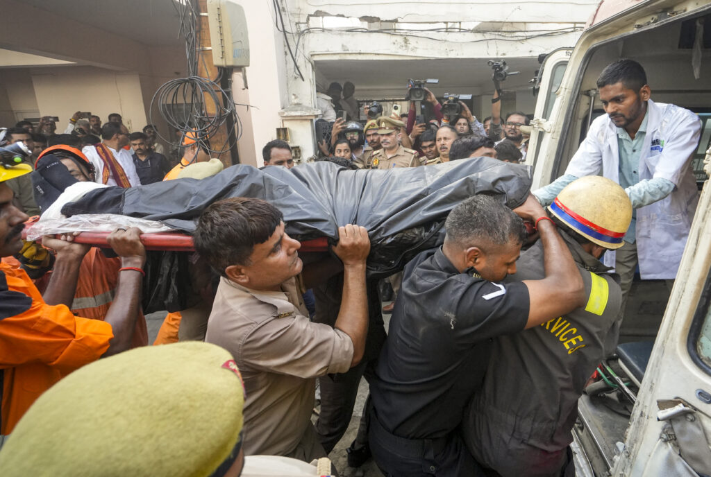Rescue workers and police carry a body bag from the scene of a fire in Lucknow.