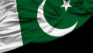 Pakistani flag waving with green, white, star, and crescent symbols.