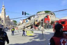 Collapsed building and emergency responders at the scene of a disaster in an urban area.