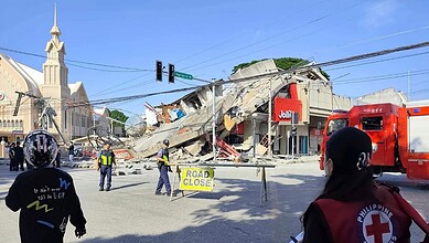 Collapsed building and emergency responders at the scene of a disaster in an urban area.