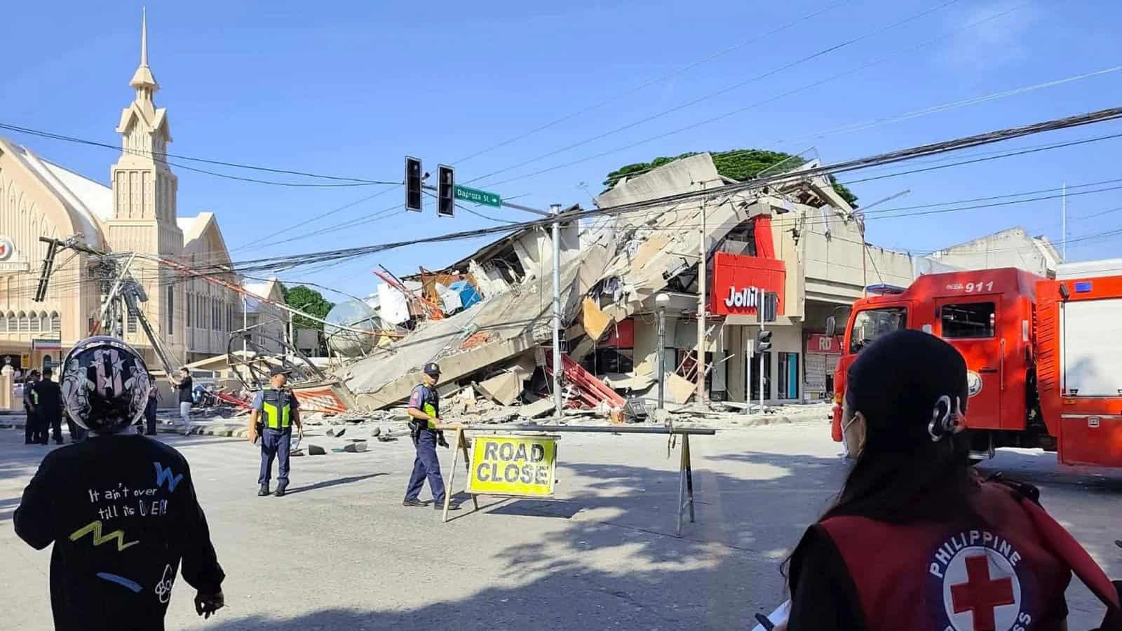 Collapsed building and emergency responders at the scene of a disaster in an urban area.