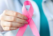 Pink ribbon for breast cancer awareness held by a healthcare professional.