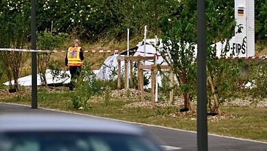 Emergency responders investigate crash site of skydiving plane in France with wreckage and safety tape.