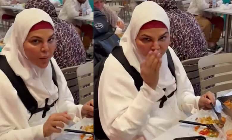 Woman in white hijab covering her head, eating food at a crowded restaurant table.