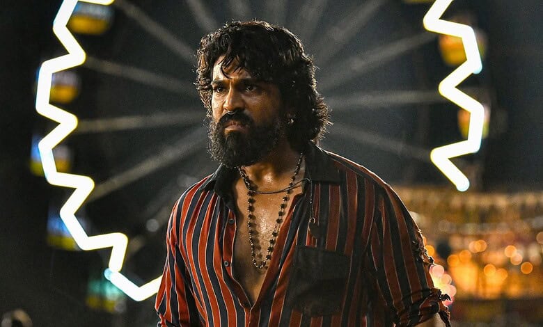 Ram Charan in a striped shirt with a serious expression at an event.