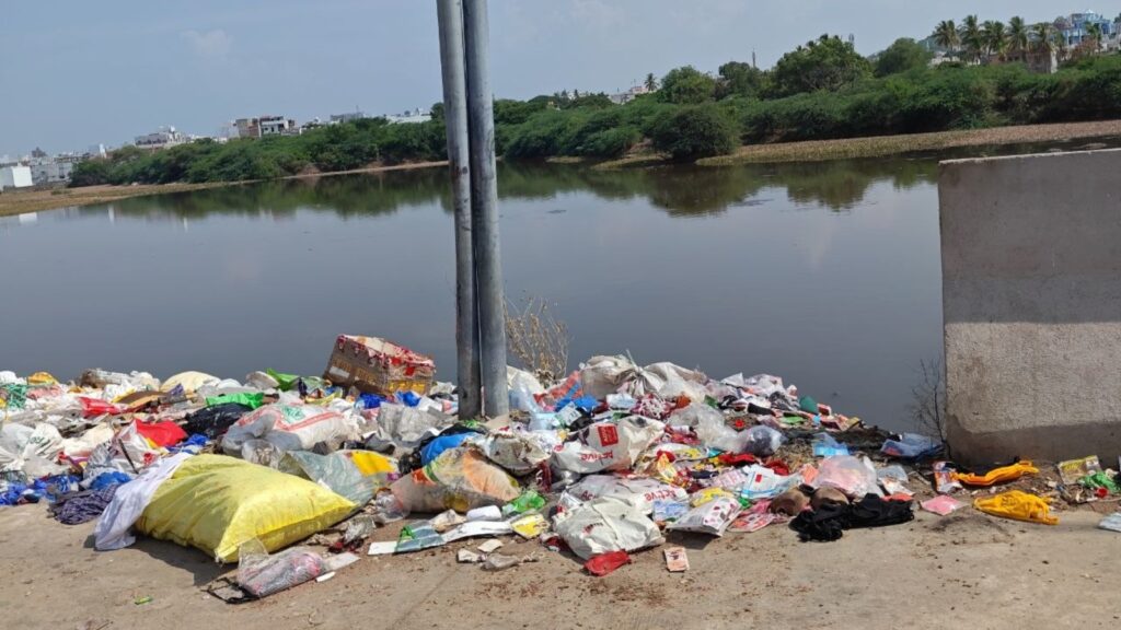 Trash and plastic waste dumped along a riverbank in Hyderabad.