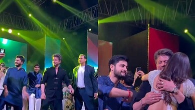 Group of people celebrating on stage with bright lights and colorful background.