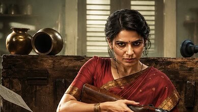 Samantha in traditional attire holding a book, with a serious expression in a rustic setting.