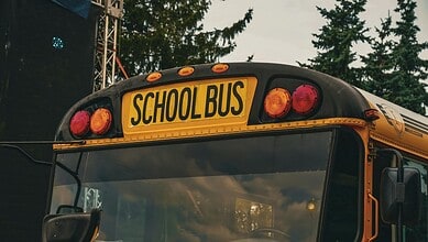 Yellow school bus with 'SCHOOL BUS' sign on the back, parked outdoors.