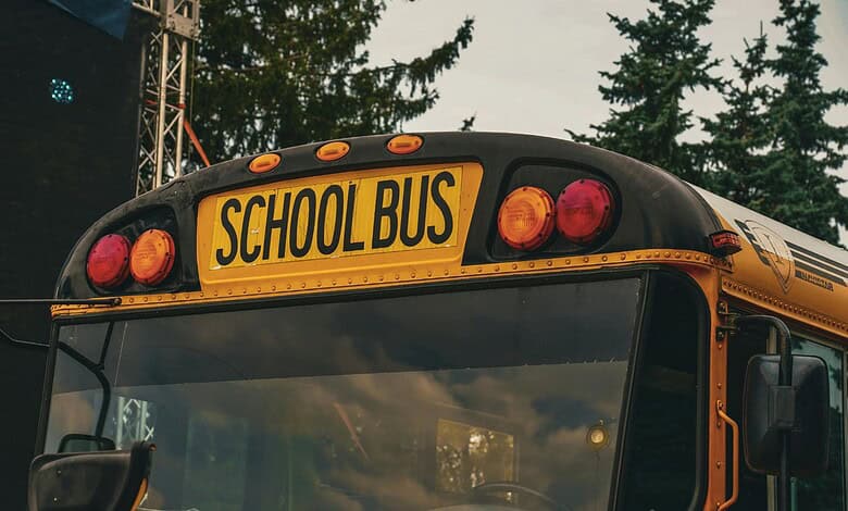 Yellow school bus with 'SCHOOL BUS' sign on the back, parked outdoors.