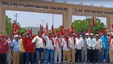 Protesters holding red flags and banners gather at the government office entrance in Hyderabad, demonstra.