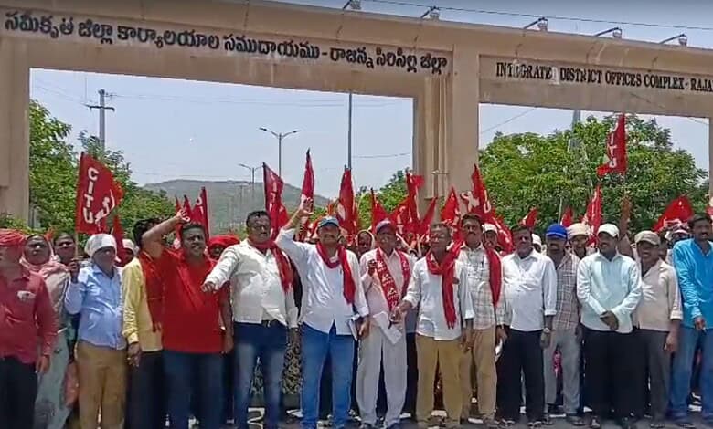 Protesters holding red flags and banners gather at the government office entrance in Hyderabad, demonstra.