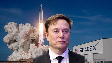 SpaceX rocket launch with Elon Musk in front, clear blue sky, and SpaceX building in background.