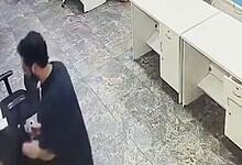 Man withdrawing cash from ATM at bank counter indoors.
