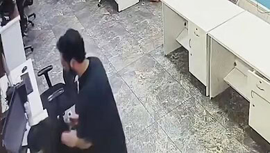 Man withdrawing cash from ATM at bank counter indoors.