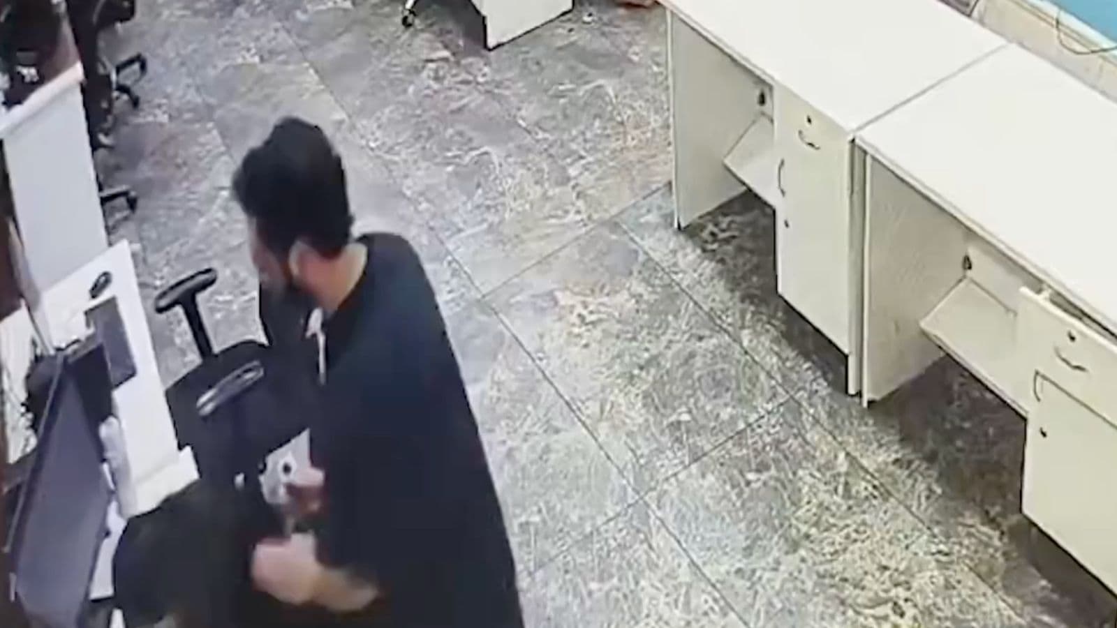 Man withdrawing cash from ATM at bank counter indoors.