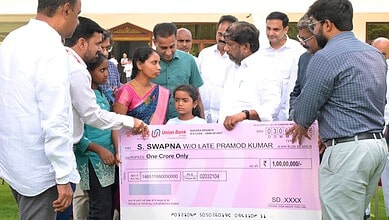 S. Swapna receiving a cheque from officials at a formal event in India.