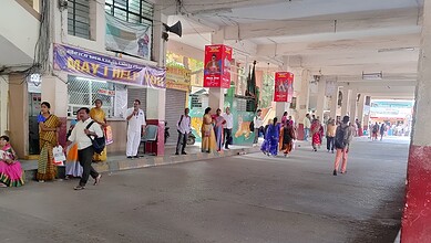 People waiting at a bus stop under a flyover in Hyderabad, India.