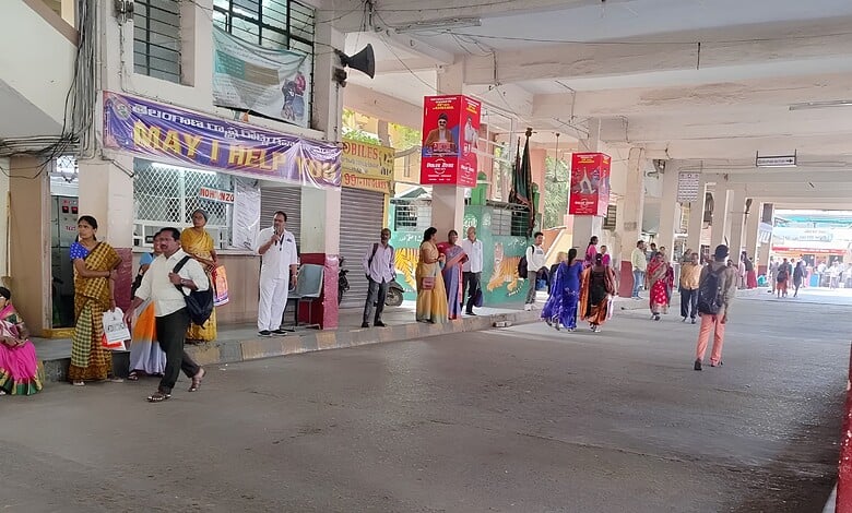 People waiting at a bus stop under a flyover in Hyderabad, India.