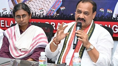 TPCC chief speaking into microphone during a political event with a woman beside him.