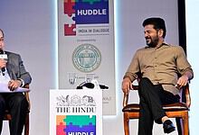 Prominent speaker at India dialogue event engaging in discussion with a young participant on stage.