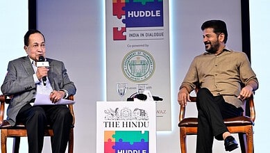 Prominent speaker at India dialogue event engaging in discussion with a young participant on stage.