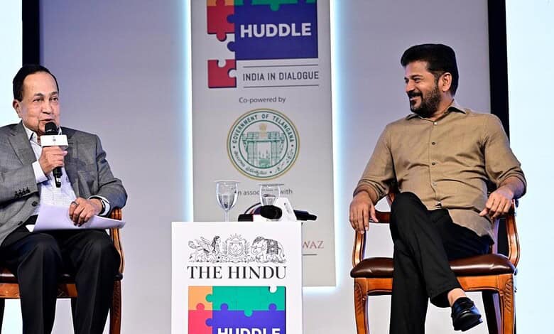 Prominent speaker at India dialogue event engaging in discussion with a young participant on stage.