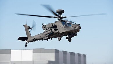 Aero combat helicopter flying above urban buildings during daytime.