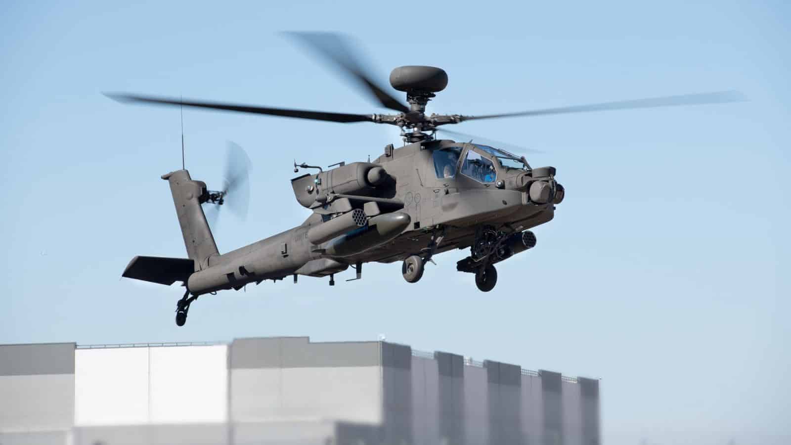 Aero combat helicopter flying above urban buildings during daytime.