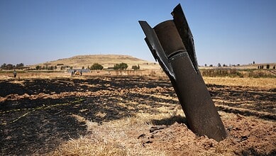 A bombed-out missile lying in a scorched field after an explosion.
