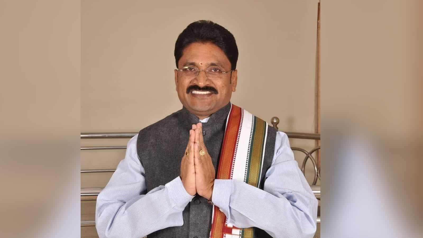 Prominent Indian politician smiling with hands folded in traditional greeting, wearing a grey vest and co.