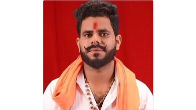 A young Indian man with a beard and moustache, wearing traditional attire and a tilak on his forehead, ag.