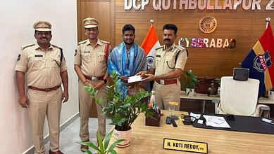 A man receiving an award from police officers in an office setting with flags and a wooden wall backgroun.