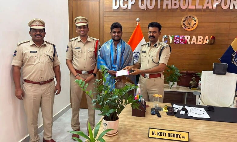 A man receiving an award from police officers in an office setting with flags and a wooden wall backgroun.