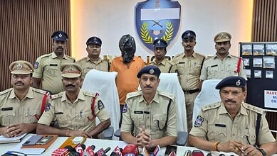 Arrested suspect in police custody with officers during a press conference at Siasat Daily.