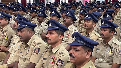 Police officers in uniform attending a formal event, standing in formation with serious expressions.
