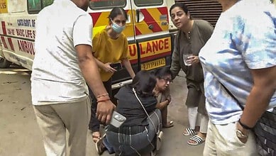 A woman receiving medical assistance from paramedics beside an ambulance on a busy street.