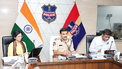 Indian police officers during a press conference at Telangana Police headquarters, with national and stat.
