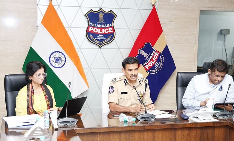 Indian police officers during a press conference at Telangana Police headquarters, with national and stat.
