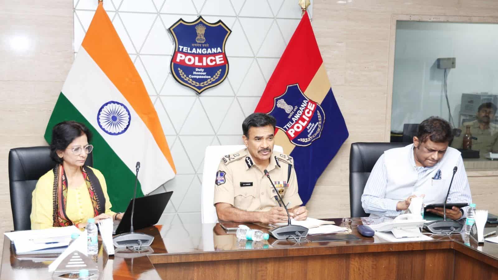Indian police officers during a press conference at Telangana Police headquarters, with national and stat.