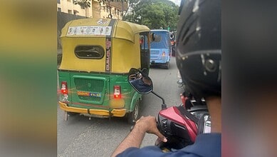 Auto rickshaw on busy city street with motorcycle rider in foreground, vibrant urban scene in the backgro.