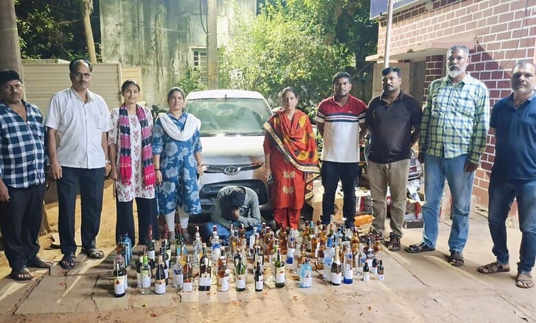 A woman kneeling among bottles of illegal alcohol seized by authorities in an outdoor setting.